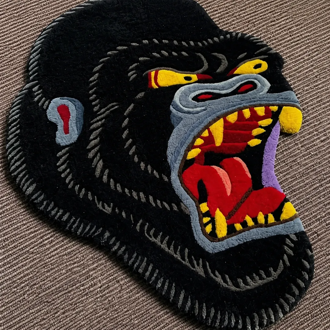 Close-up of the detailed tufted pile texture, roaring expression, sharp yellow teeth, and plush black pile on the Gorilla Head rug.