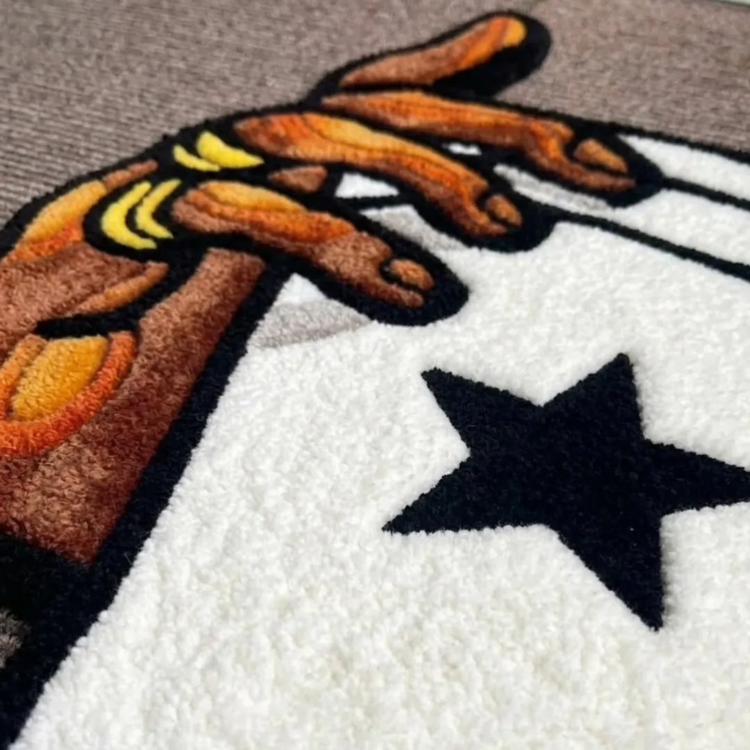 Close-up of the detailed tufted pile texture, black star design, and hand graphic on the hand holding glass swoosh rug.