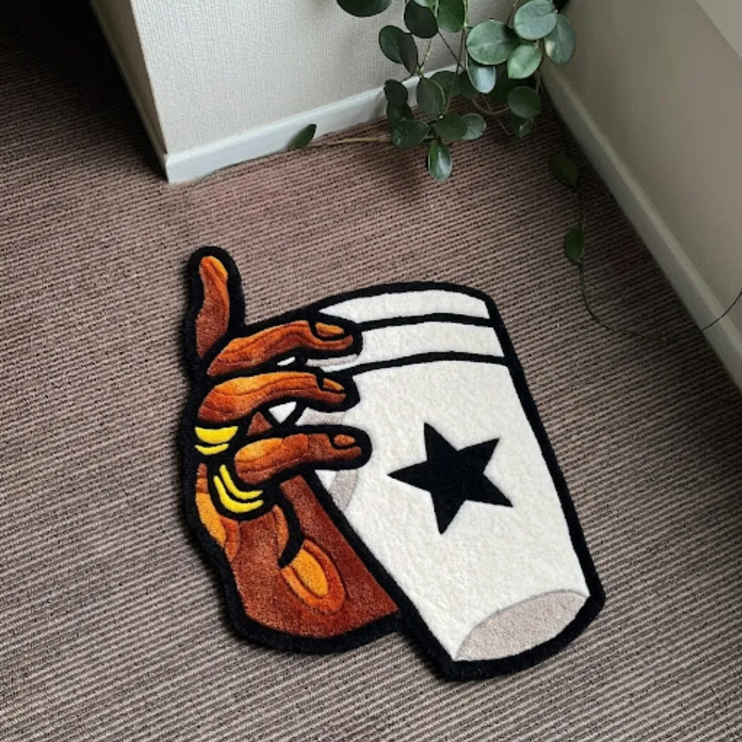 Hand holding glass swoosh shaped tufted area rug displayed flat on a carpeted floor.