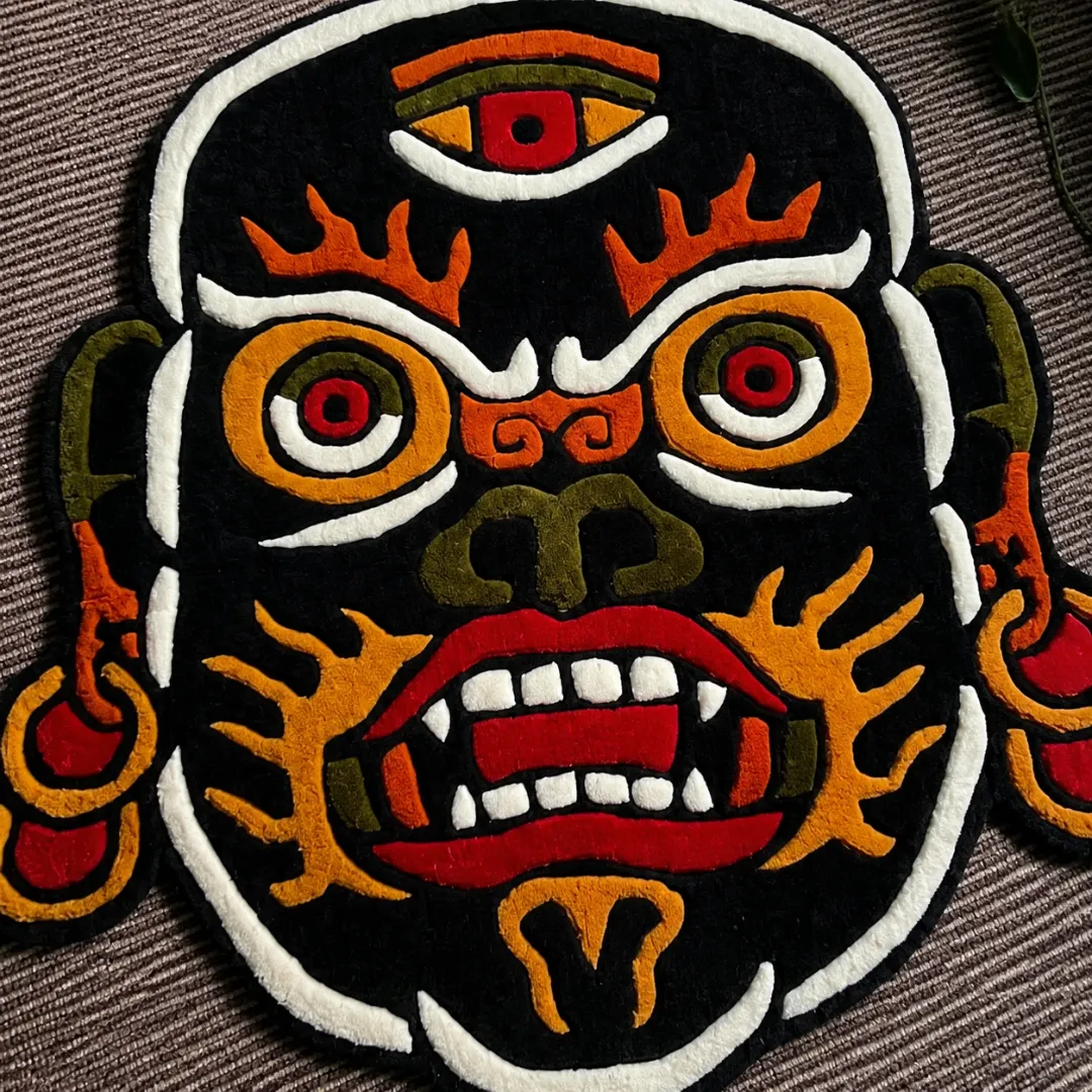 Close-up of the detailed tufted pile texture, third-eye motif, sharp teeth, and vibrant color blocking on the Mahakala rug.