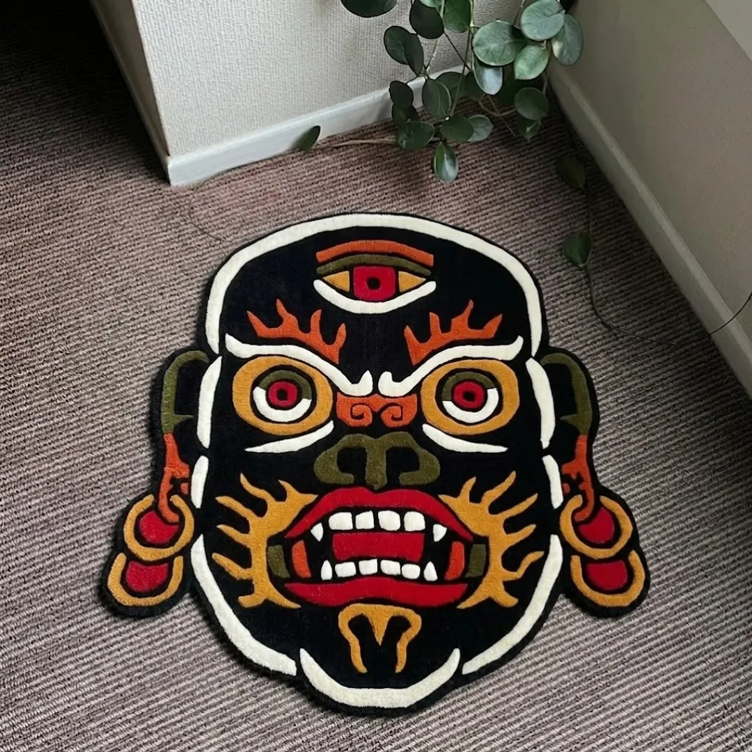 Mahakala traditional Tibetan deity style fierce masked shaped tufted area rug displayed flat on a textured carpeted floor.