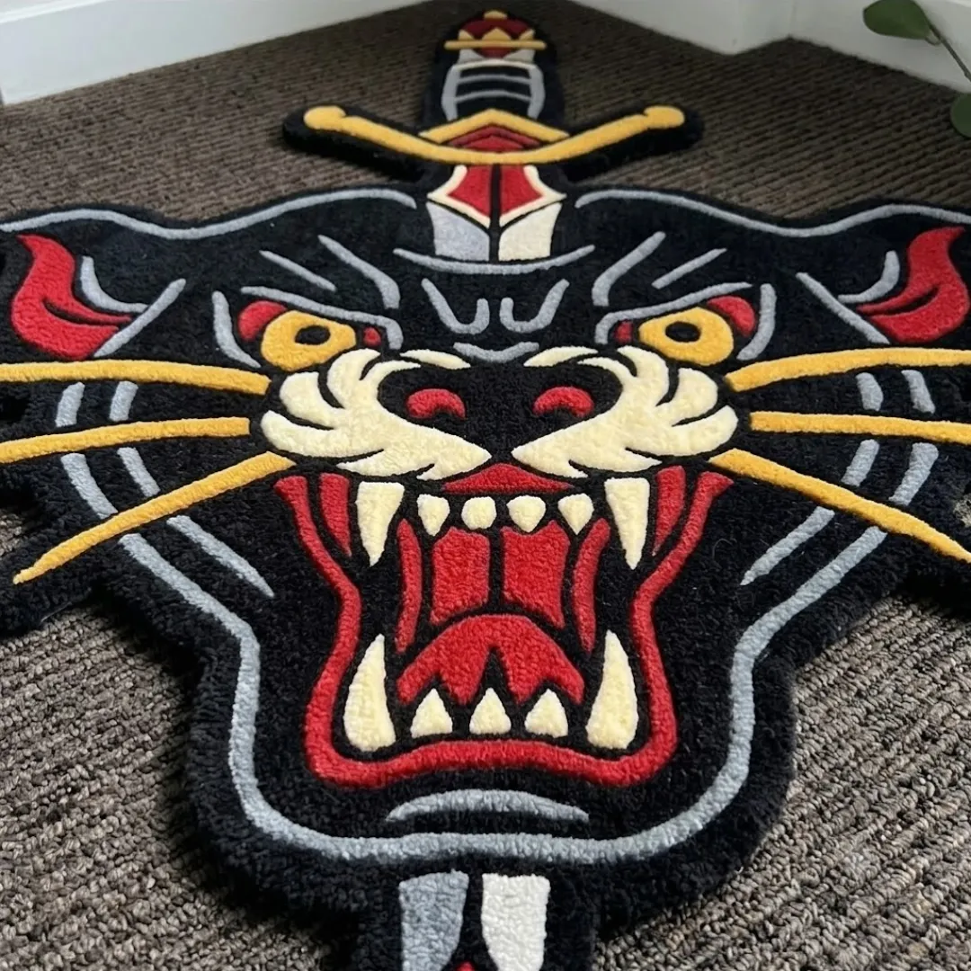 Close-up of the detailed tufted pile texture, fierce expression, and bold red and yellow color blocking on the Panther Dagger rug.