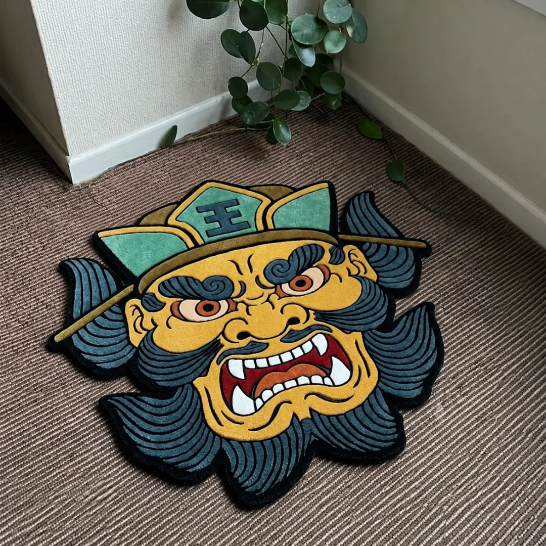 Angle view of the handmade Wrath Samurai Mask tufted rug showcasing its unique face contours and vibrant colors on a carpeted floor.