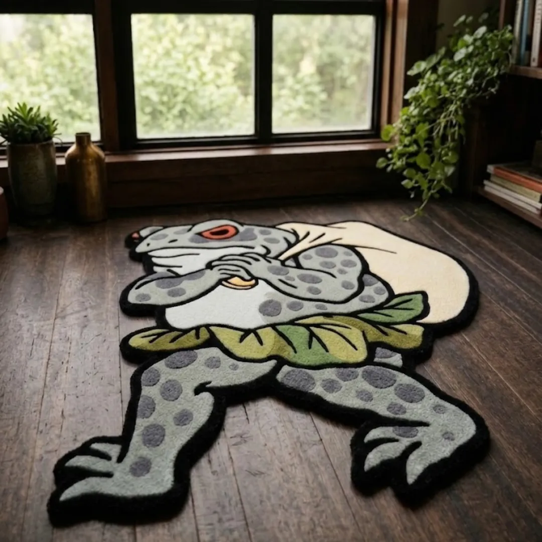An angled perspective shot of a hand-tufted backpack frog rug, highlighting its expressive character silhouette and high-quality wool texture on a wooden floor.