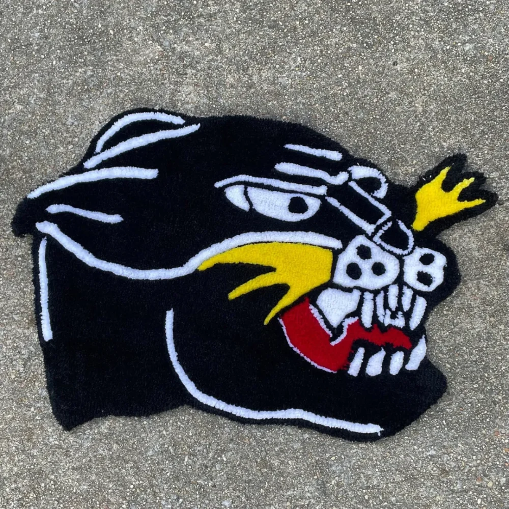 Detail hand-tufted black panther head rug with sharp teeth, yellow details, and bold red mouth inspired by classic tattoo art