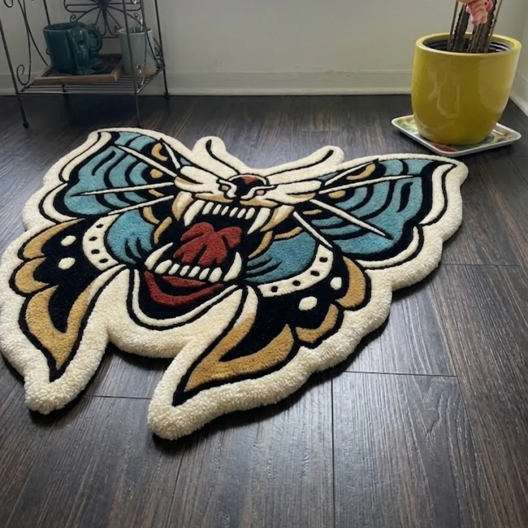 An angled perspective shot of a hand-tufted death moth roar rug, highlighting its expressive moth silhouette and high-quality wool texture on a dark wood floor.
