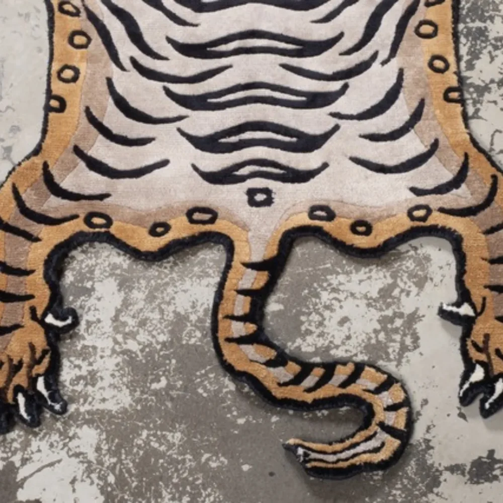 Brown Tibetan-style tiger rug with black stripes, red face details, and a playful smile.
