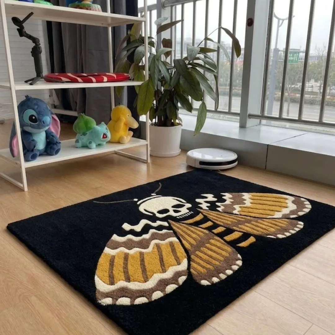 A perspective view of a rectangular skull moth area rug with intricate gold and brown wing details, displayed on light wooden flooring.