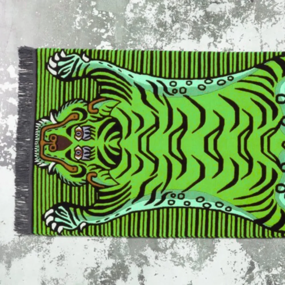 Green tibetan tiger-shaped rug with black stripes and striped background – bold floor décor.