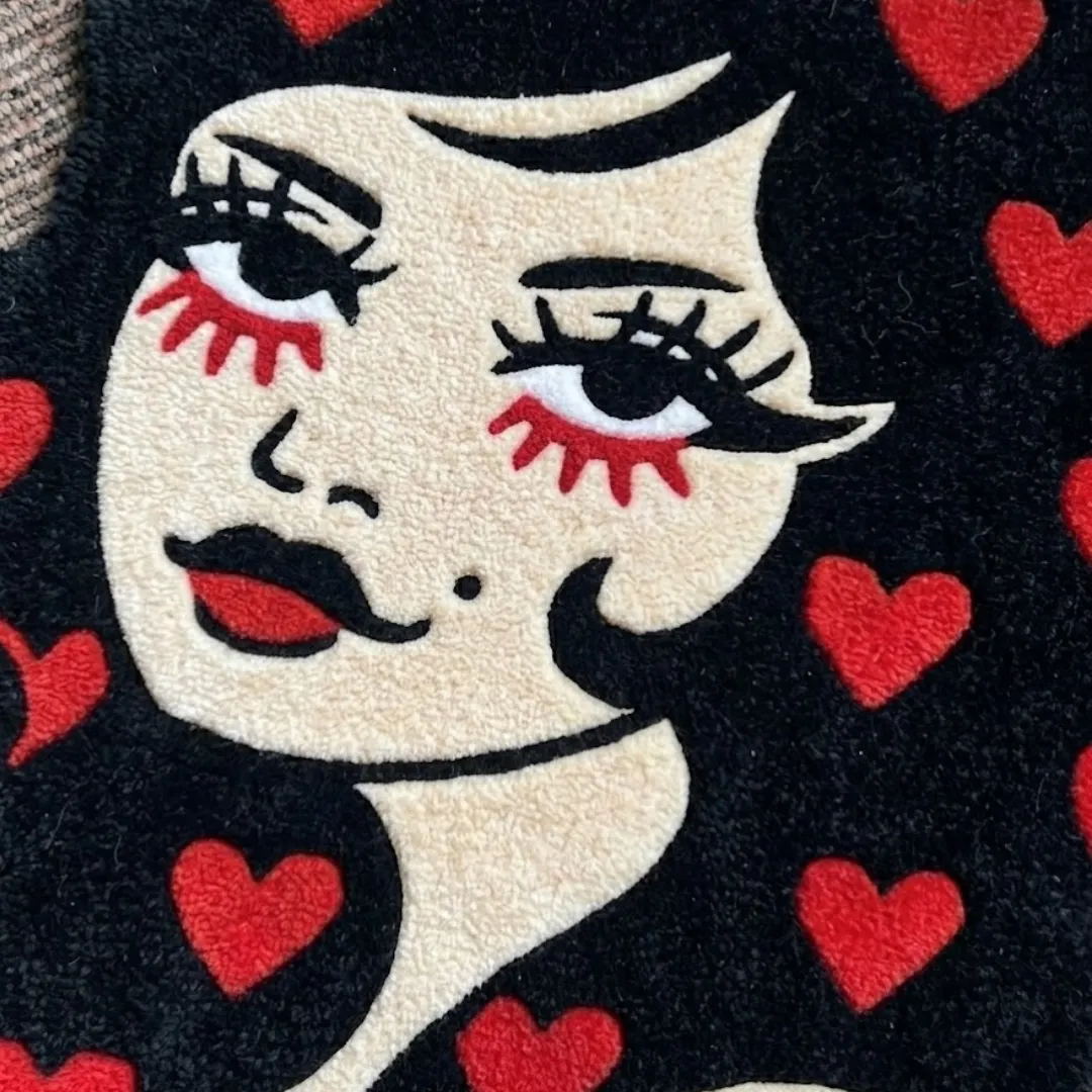 A macro close-up of the love lady rug, focusing on the dense, tufted wool pile and the intricate graphic design of the woman's face and heart-patterned hair.