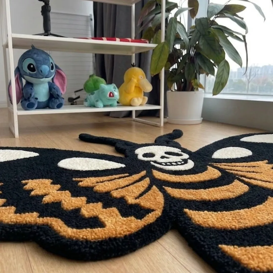 An angled perspective shot of a hand-tufted orange death moth rug, highlighting its expressive moth silhouette and the high-quality wool texture on a wooden floor.