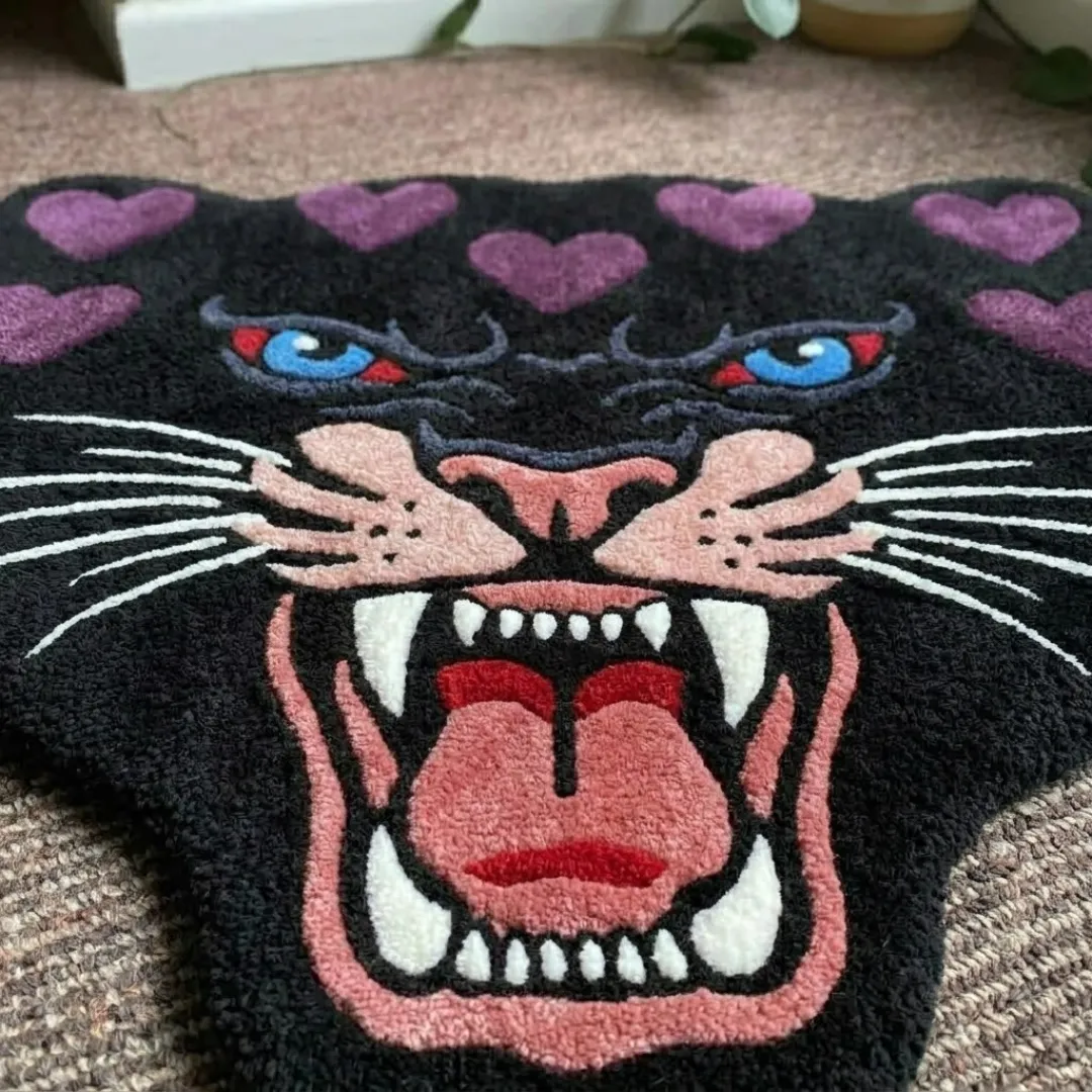 A macro close-up of the purple panther head rug, focusing on the dense, tufted wool pile and the detailed graphic linework of the panther's face, purple heart markings, and snarling expression.