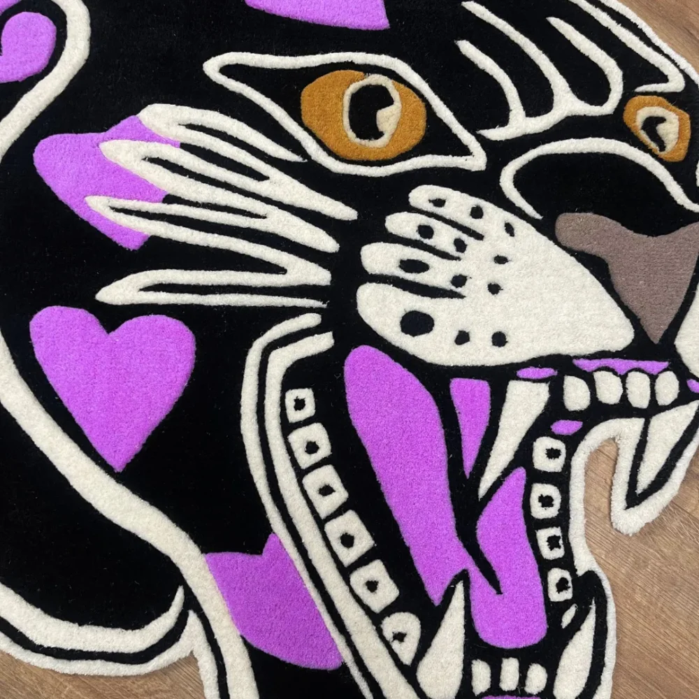Custom-shaped panther head rug with black background and purple heart patterns, featuring fierce teeth and golden eyes in a tattoo-inspired design laid on wooden floor.