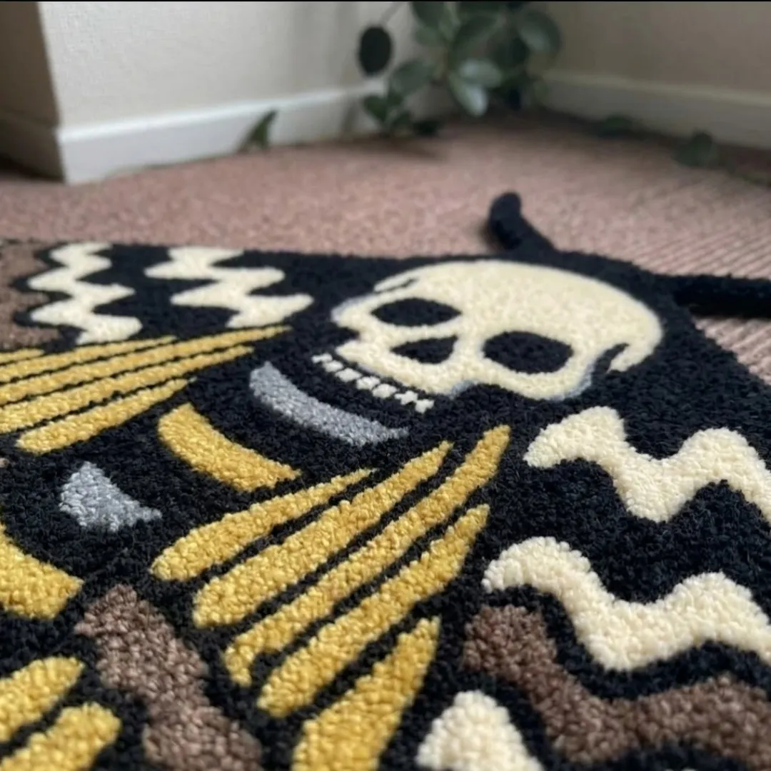 A macro close-up of the skull moth rug, focusing on the dense, tufted wool pile and the intricate graphic design of the skull and moth wings.