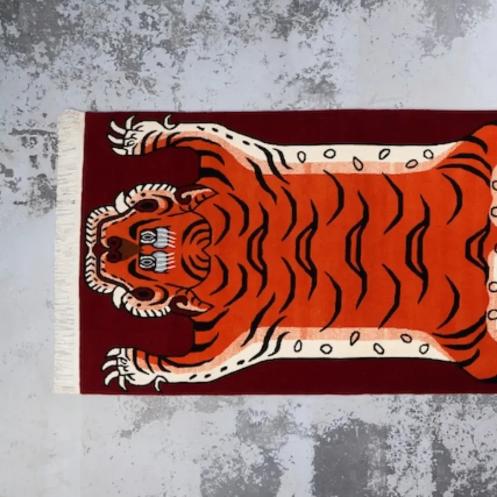 Hand tufted Tibetan tiger rug with orange tiger on red background, used for meditation and protection.