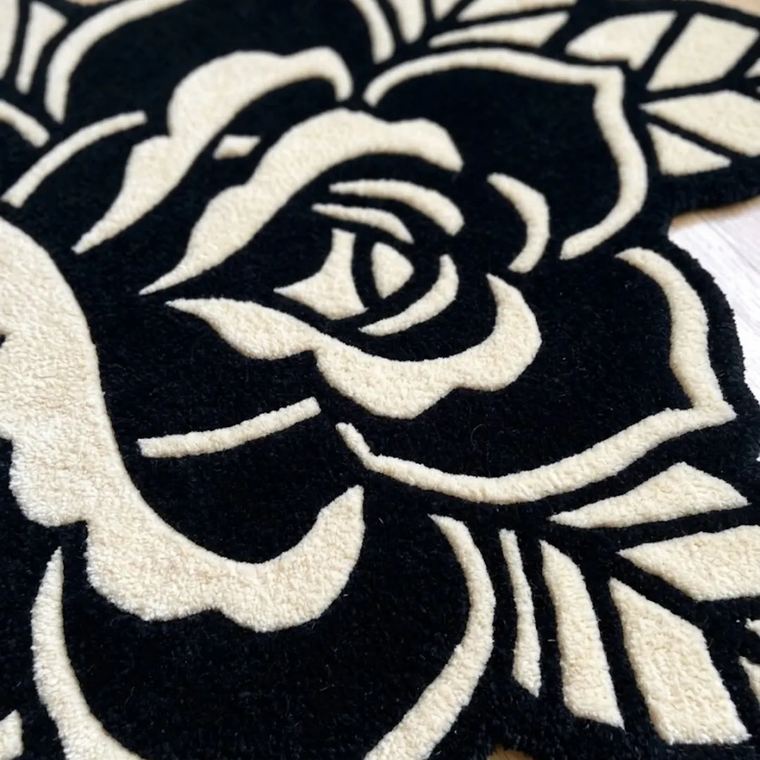 A detailed macro close-up of the black rose rug, showcasing the dense, high-quality tufted wool texture and the contrast between the black and cream color blocks.
