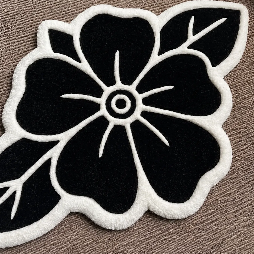 Angle view of the handmade Blackwork Rose tufted rug showcasing its unique organic contours and bold tattoo-inspired design on a carpeted floor.