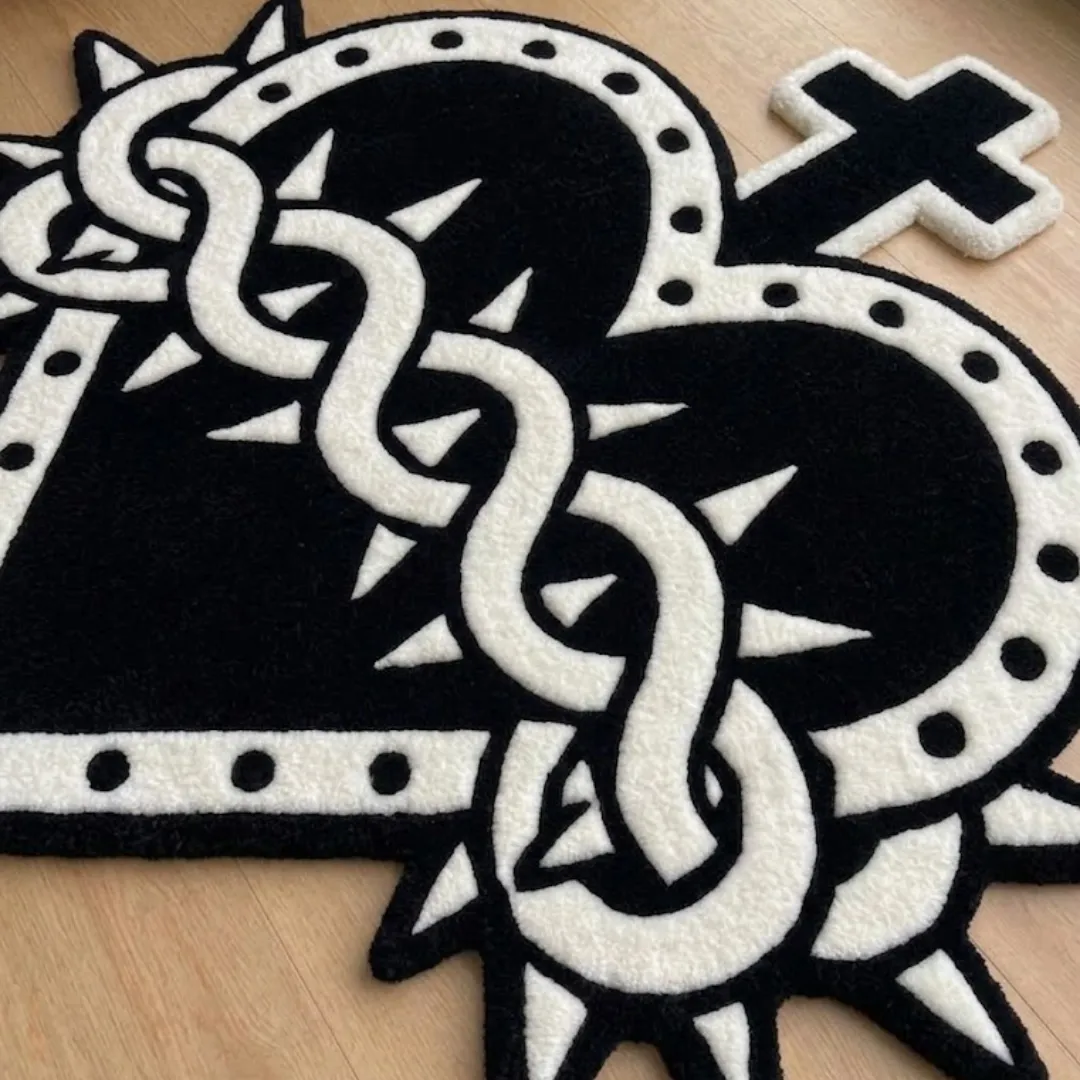 A macro close-up view of the cross-and-heart rug, highlighting the dense, high-quality tufted wool texture and the sharp, graphic black-and-white outline of the gothic design.