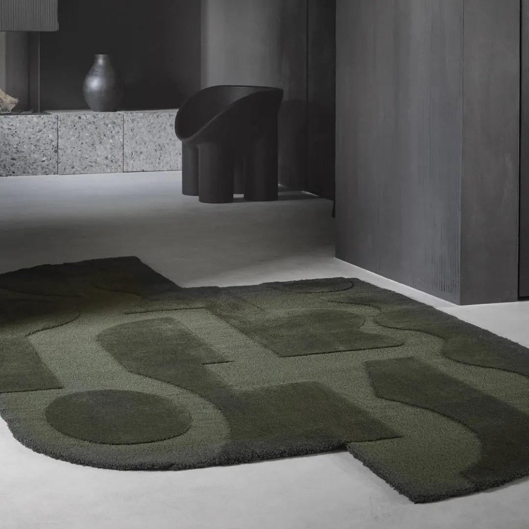 Bold geometric rug with abstract figures and dark green colors.