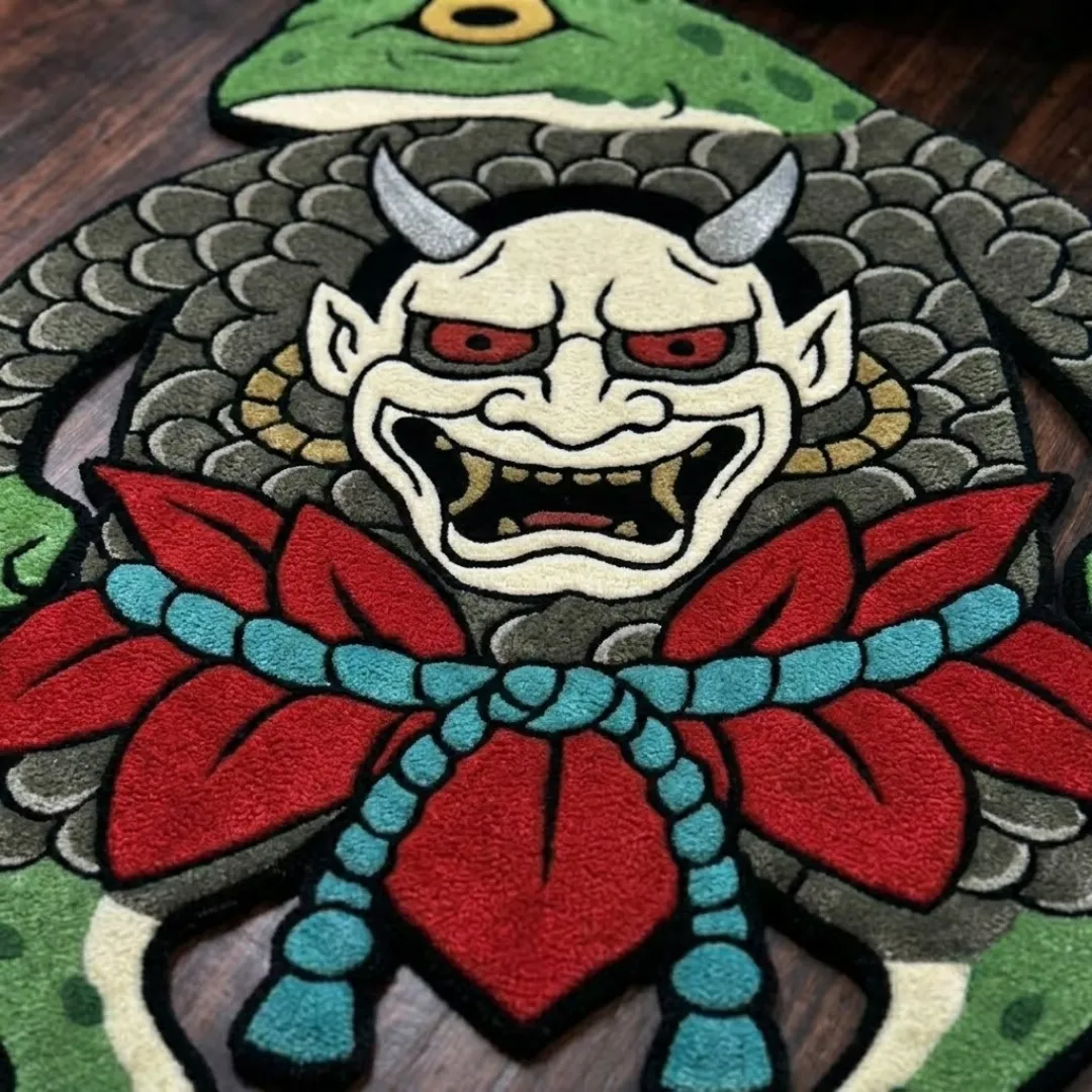 A macro close-up of the frog demon rug, highlighting the dense, high-quality tufted wool texture and the intricate graphic linework of the demon mask, red floral elements, and scaled body pattern.