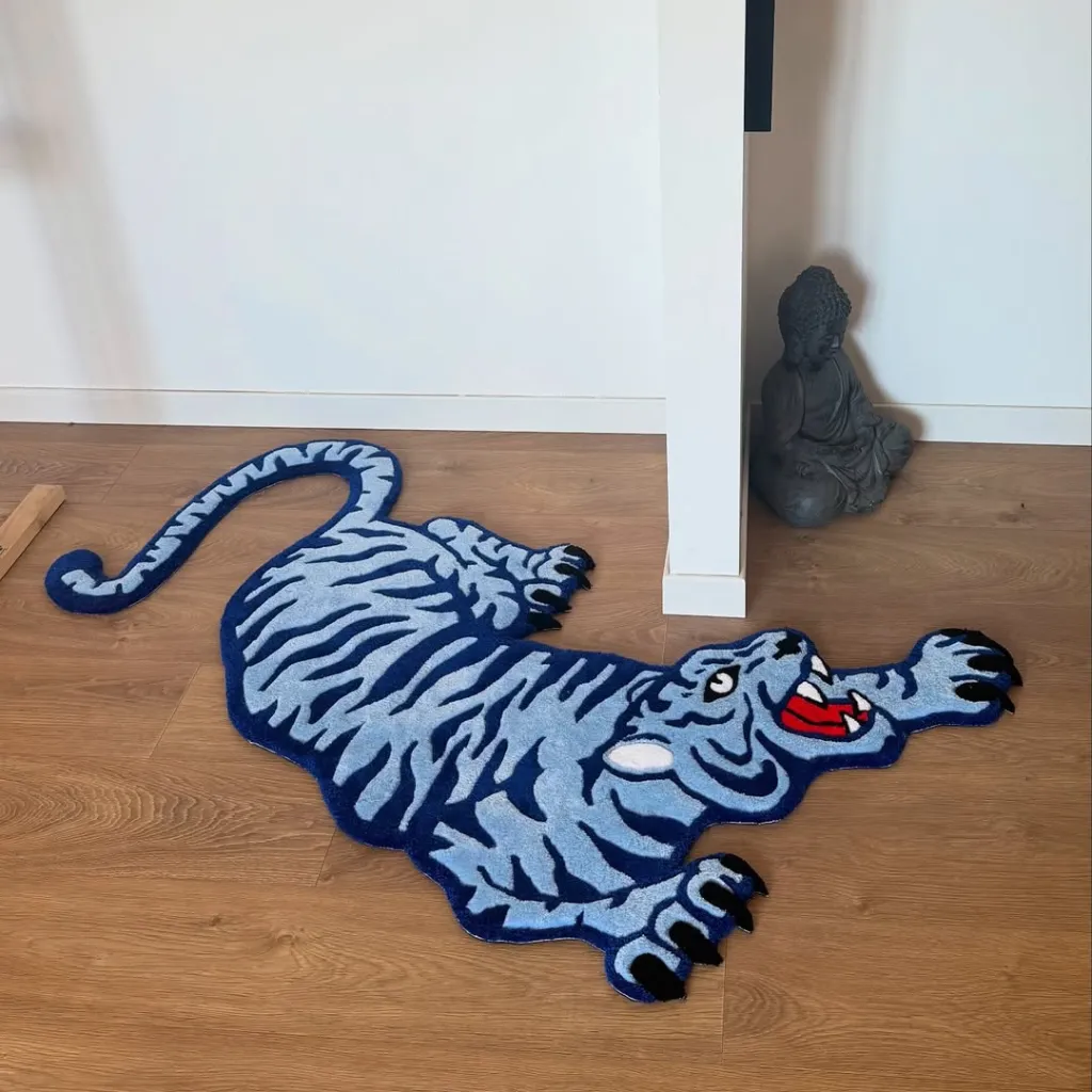 High angle view of the custom shaped Cool Fang rug featuring a stylized blue tiger design displayed on a wooden floor next to a Buddha statue.