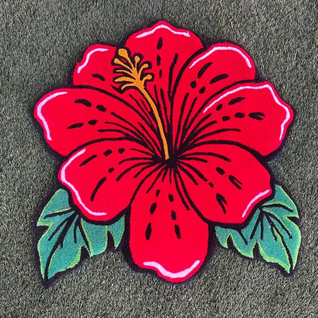 Top down view of the custom shaped Ember Petal rug featuring a vibrant red hibiscus flower design with green leaves on a dark background.