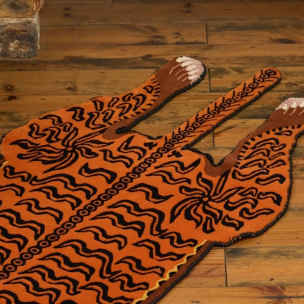 Close-up detail of the rear section of the Amber Raja rug, showing the hand-tufted texture of the tiger's tail and hind legs with stylized claw details.
