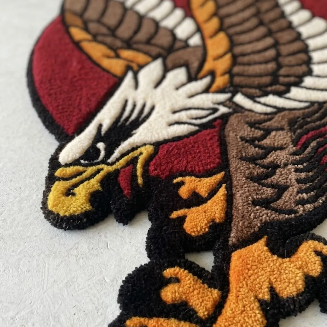 Close up angled view of an American eagle traditional rug highlighting the textured yarn details of the white feathered head, yellow beak, and orange talons.