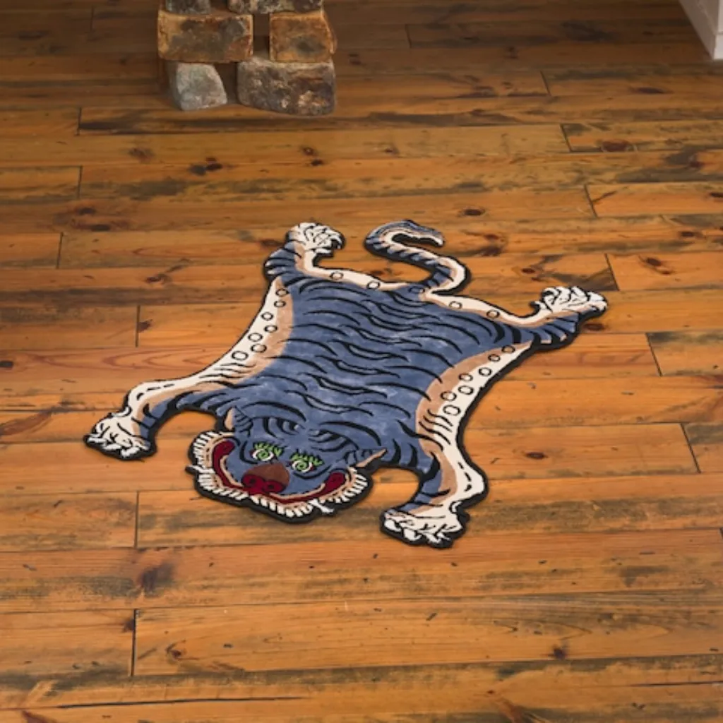 High angle view of the full Ashen Claw rug placed on a rustic wooden floor, showcasing the traditional Tibetan tiger skin shape in a muted blue-grey and tan color palette.