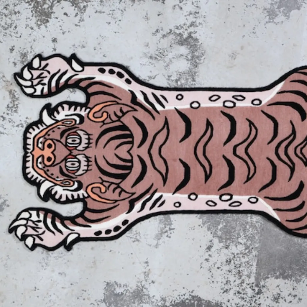 High angle view of the full Blush Prowl rug placed on a rustic wooden floor, showcasing the traditional Tibetan tiger skin shape reimagined in a contemporary pastel pink and black colorway.