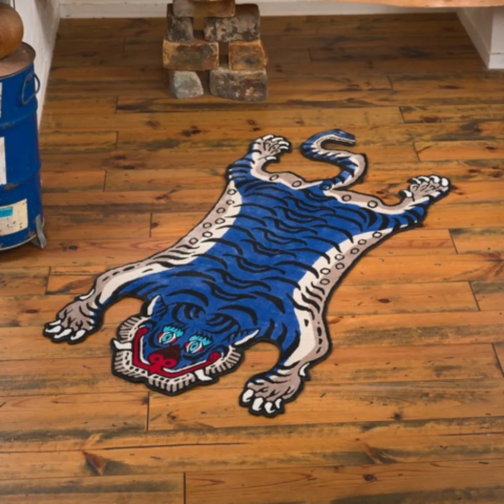 High angle view of the full Cobalt Fang rug placed on a rustic wooden floor, showcasing the traditional Tibetan tiger skin shape re-imagined in a bold blue and white colorway.