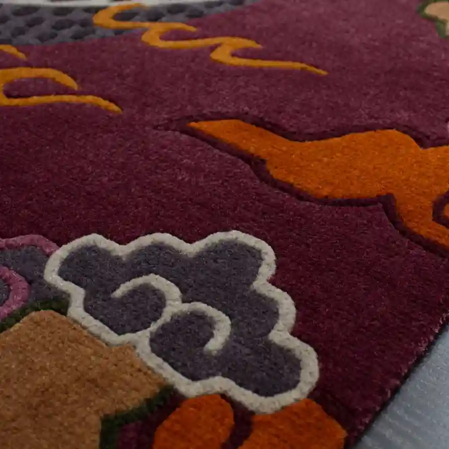 Extreme close up of the hand tufted wool texture on the Crimson Omen rug, focusing on the dense cut pile of the purple background and the precise carving of the cloud borders.