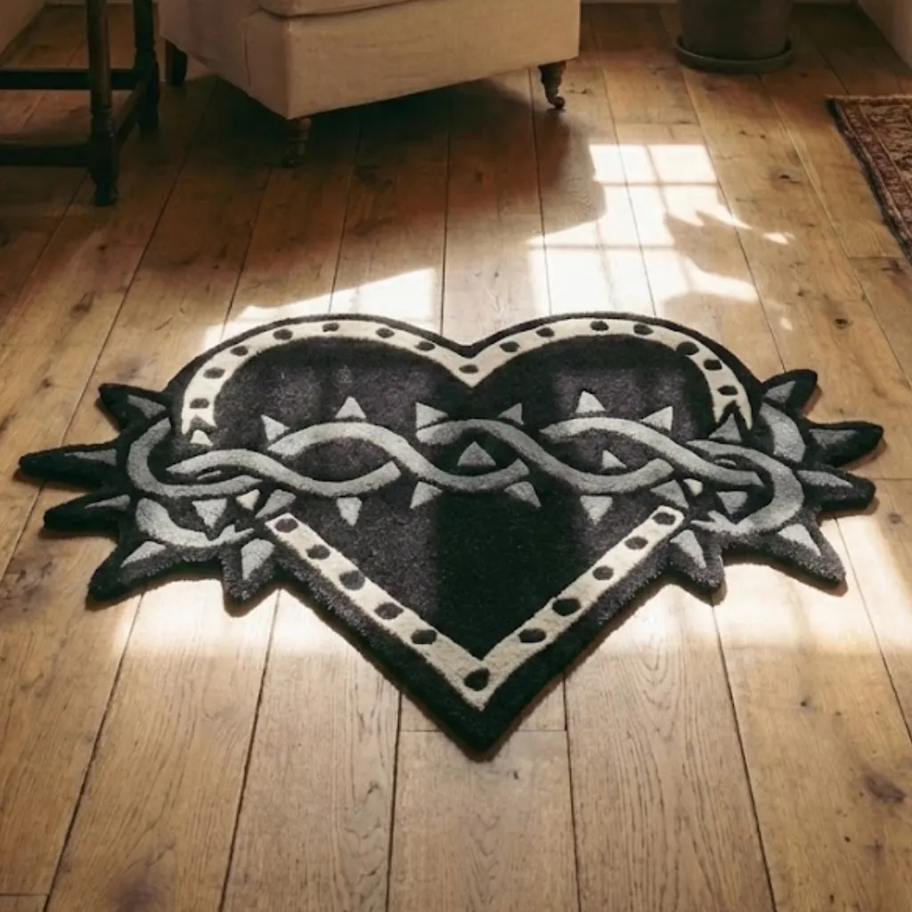Angled view of the Thorned Heart shaped rug placed on a wooden floor, highlighting the dense hand tufted wool texture and edgy gothic design elements.