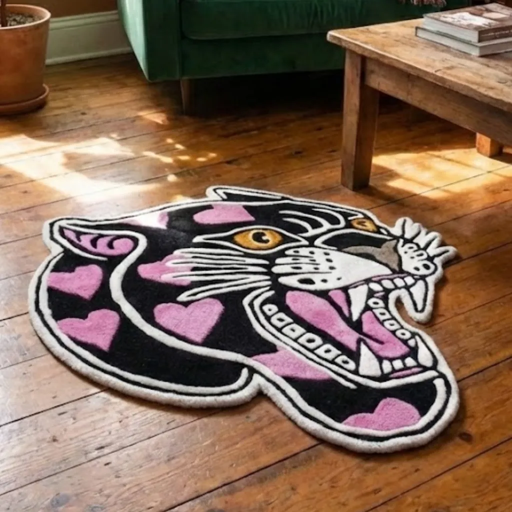 Angled view of the panther head rug with pink hearts lying on a wooden floor, highlighting the thick hand-tufted wool pile and custom die-cut shape.