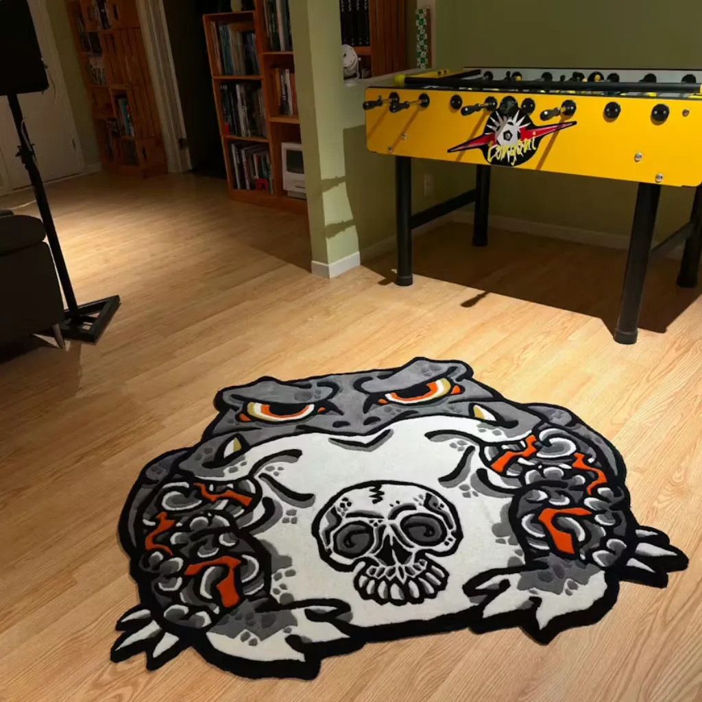 kaeru no senshi japanese toad rug gaming room High angle view of the Kaeru No Senshi rug placed in a recreation room, featuring a bold Japanese tattoo-style toad design with a skull motif in grey, black, and orange.