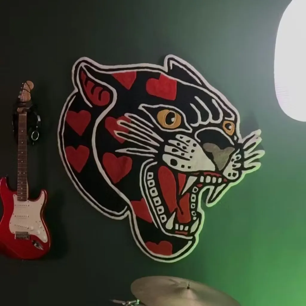 The Red Panther rug displayed as a statement wall hanging next to an electric guitar, illustrating its versatility as edgy, rock-inspired room decor.