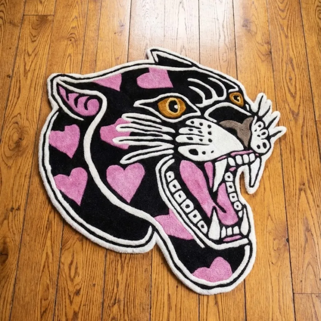 Top down view of a hand tufted rug shaped like a roaring black panther head filled with pink hearts, featuring a classic American traditional tattoo design.