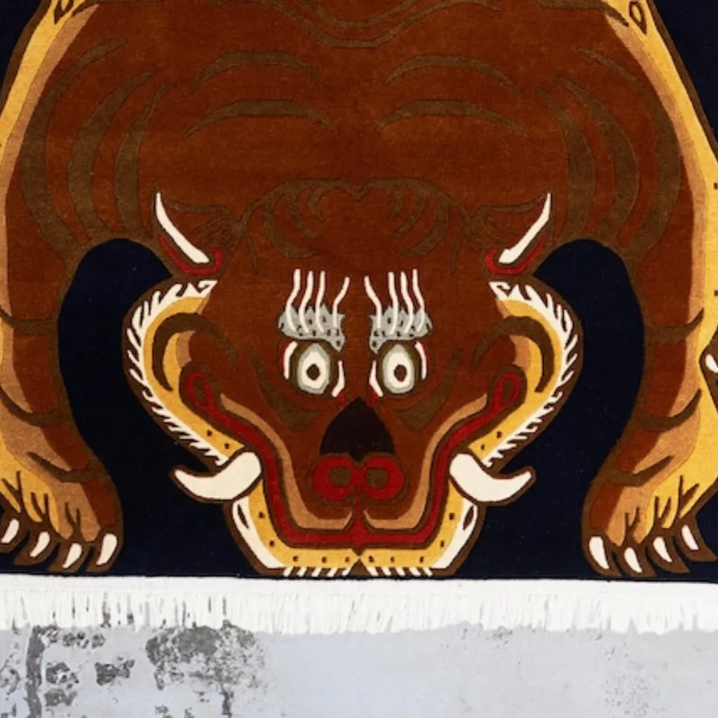 rooted fang green tibetan tiger rug head detail Close-up top down view of the Rooted Fang Tibetan Rug, focusing on the stylized tiger face with intense eyes and black wavy stripes set against a deep moss green background.