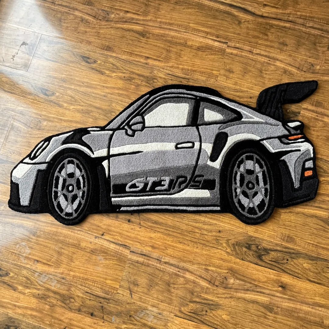Top down view of the Apex Race rug shaped like a silver Porsche 911 GT3 RS sports car, featuring detailed black accents, a large rear wing, and side branding.