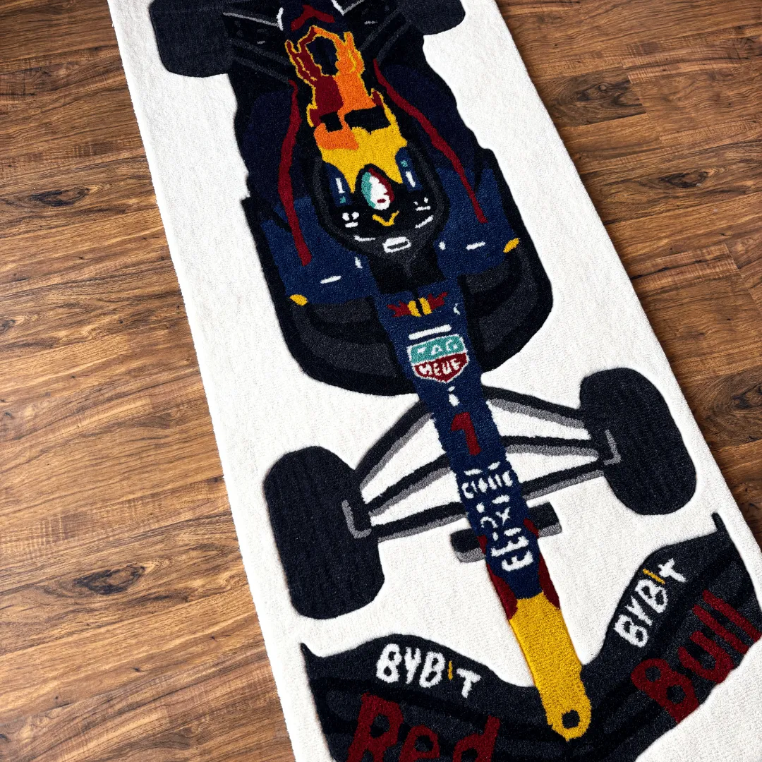 apex surge rug car nose detail Perspective view of the Apex Surge runner rug featuring a tufted illustration of a navy blue Formula 1 race car with red and yellow accents and Red Bull branding.