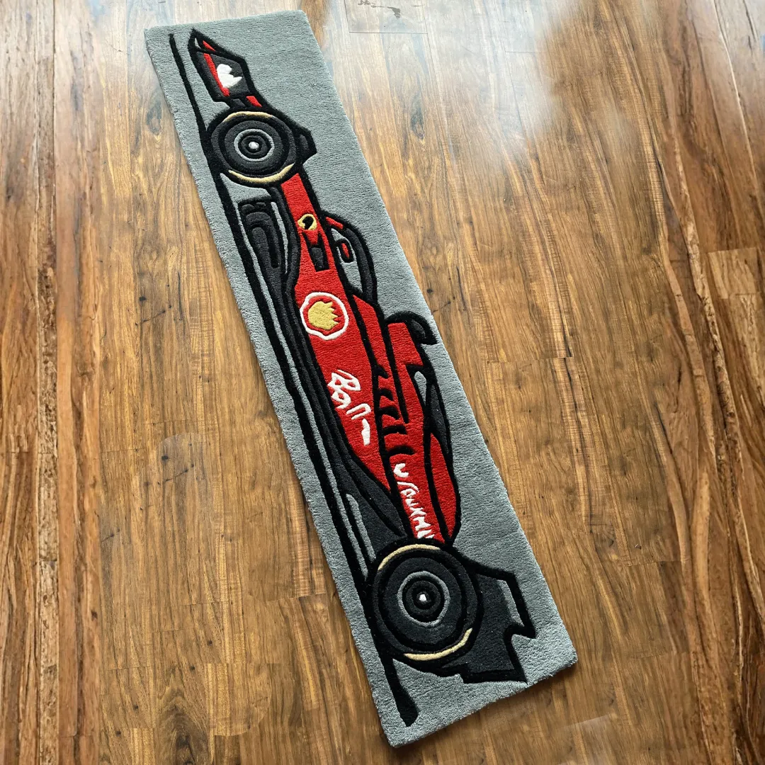 Top down view of the Asphalt Aura runner rug featuring a stylized red Formula 1 race car illustration on a grey asphalt-colored background.