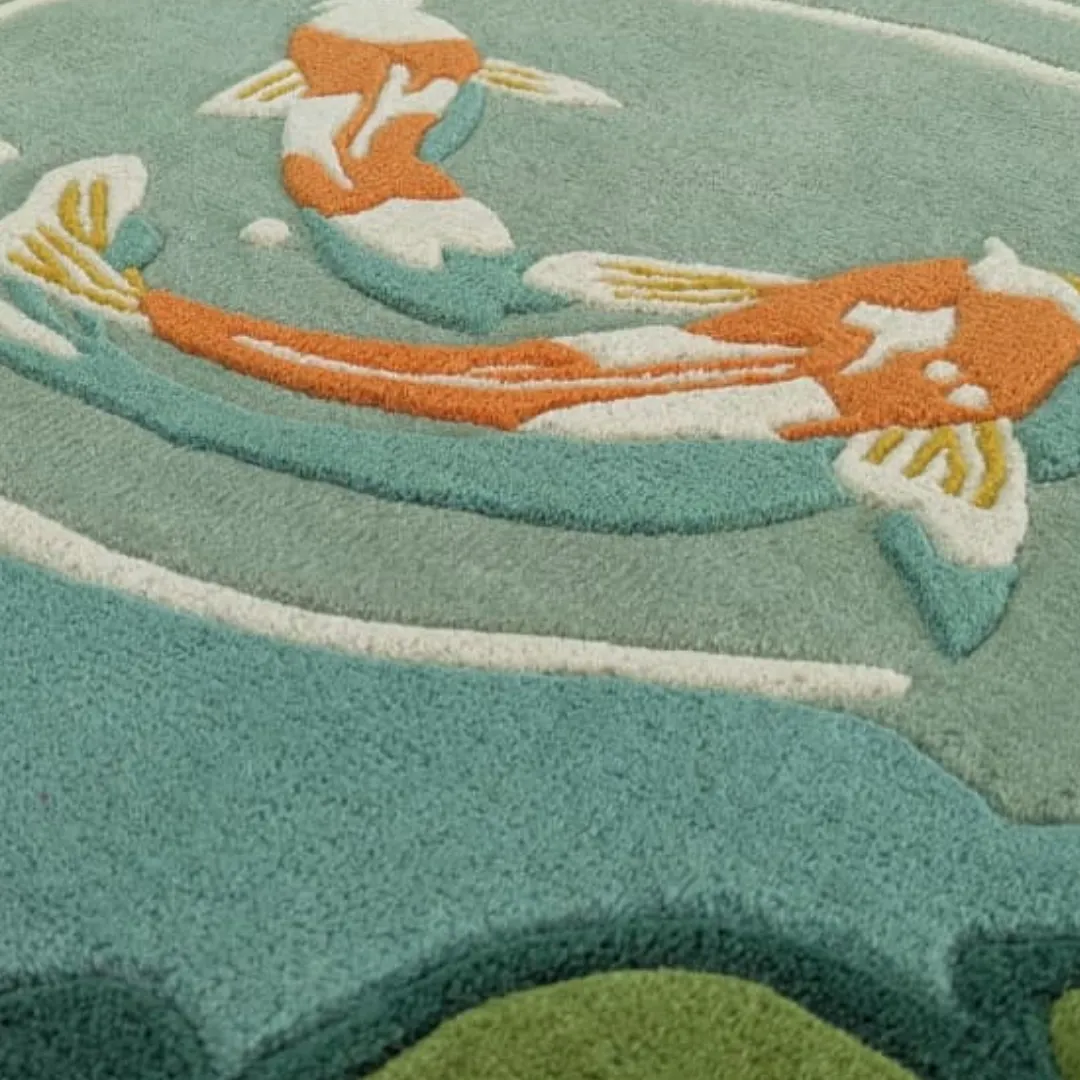 Close-up detail of the Mizu Garden rug showing the intricate hand-tufted texture of the orange koi fish and the precise carving of the water ripples in soft wool.