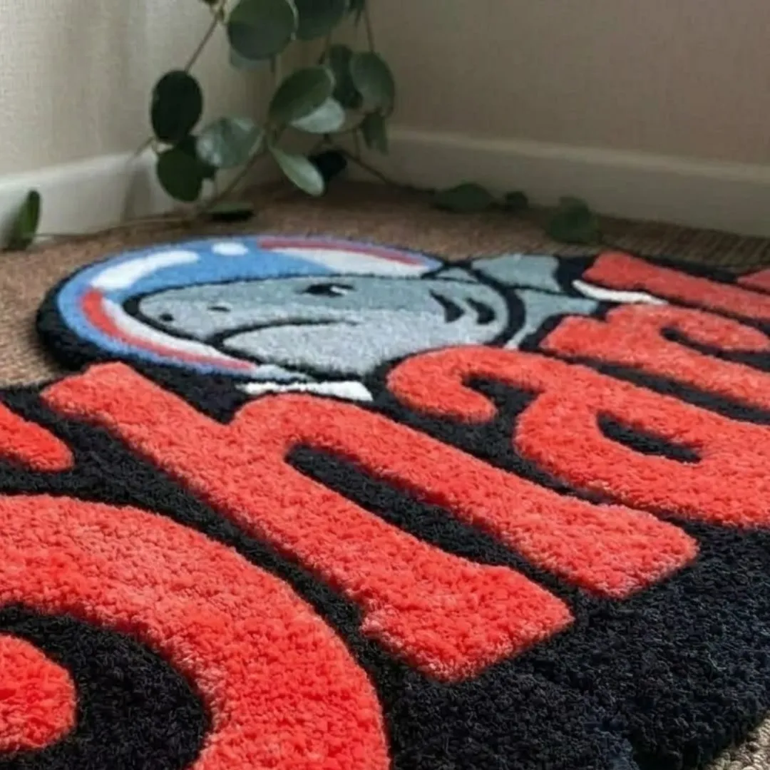 Close-up of the detailed tufted pile texture, bold red lettering, and black backing on the Primal Script rug.