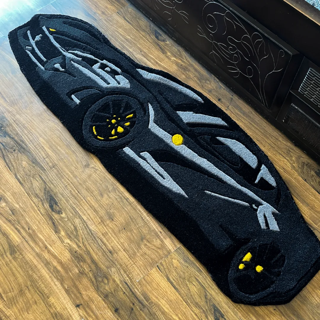 Perspective view of the Shadow Monarch rug placed on a wooden floor, highlighting the plush tufted texture and the bold black and grey supercar design.