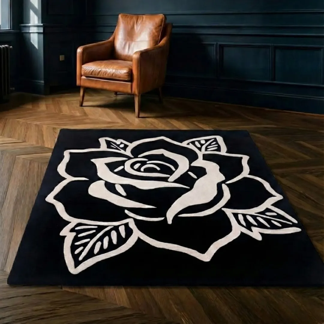 The Shadow Rose rug placed on herringbone wood flooring near a leather armchair, highlighting the contrast between the dark rug and warm wood tones.