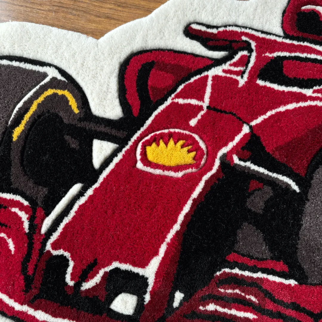 Close-up detail of the Victory Drive rug, showcasing the plush tufted texture of the red car's front nose and the yellow shield logo.