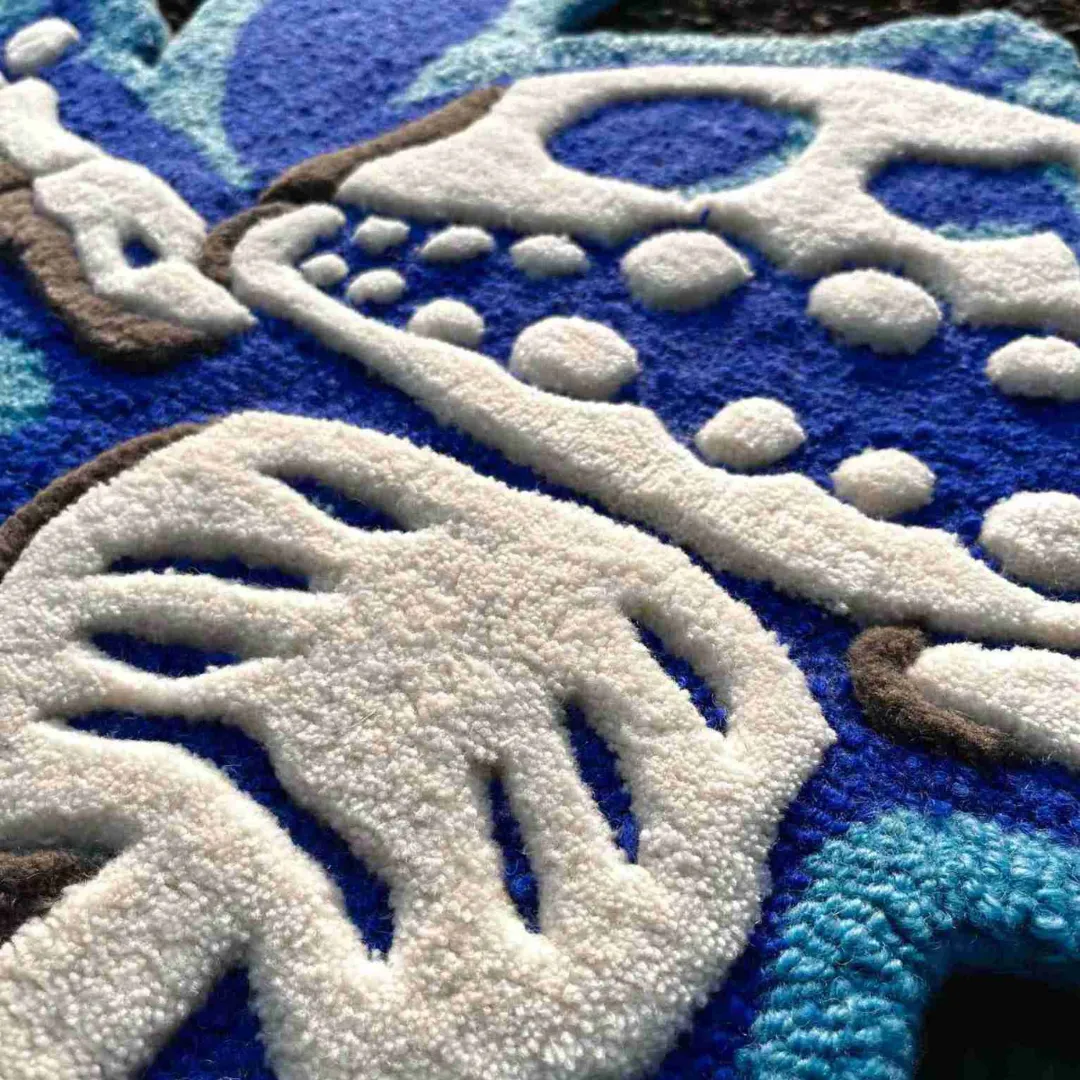 Angled close-up view of the Azure Flux rug on an asphalt surface, emphasizing the dense wool texture and the sharply carved lines defining the ribcage and bone elements of the character.