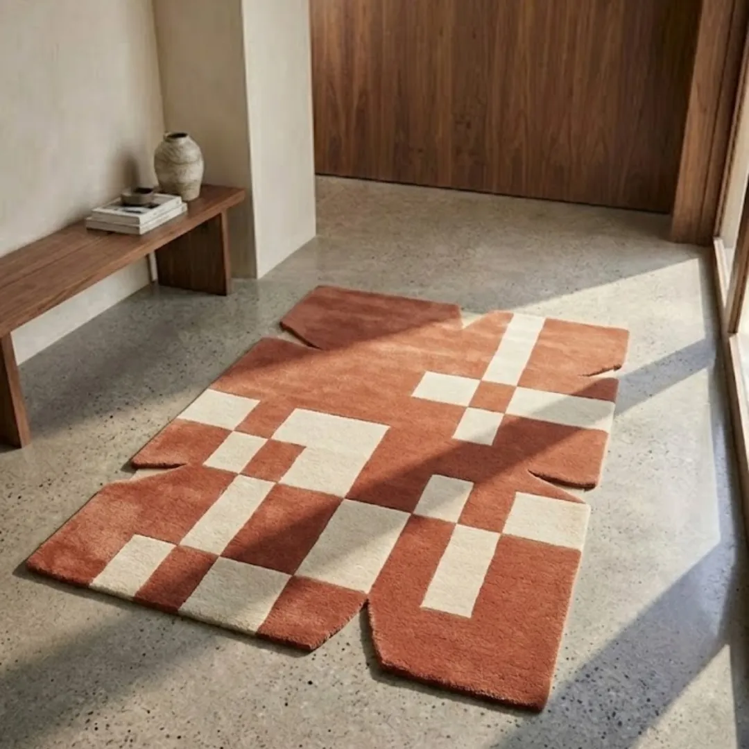Perspective lifestyle view of the Desert Codec rug placed on a polished concrete floor, showcasing the bold terracotta and cream digital-inspired pattern and its architectural jagged border.
