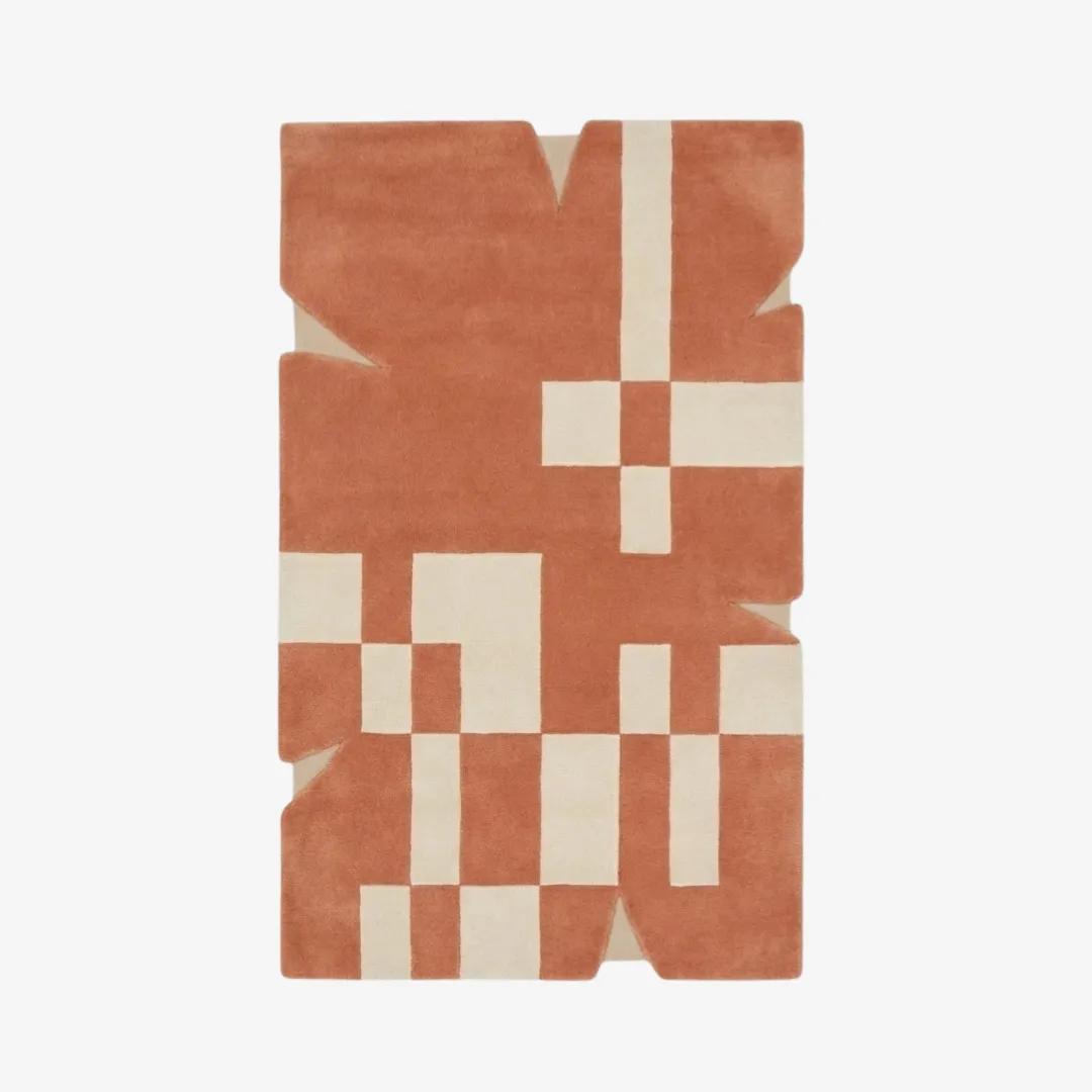 Top-down view of the Desert Codec rug featuring a warm terracotta background with ivory geometric blocks and a unique, notched irregular silhouette.