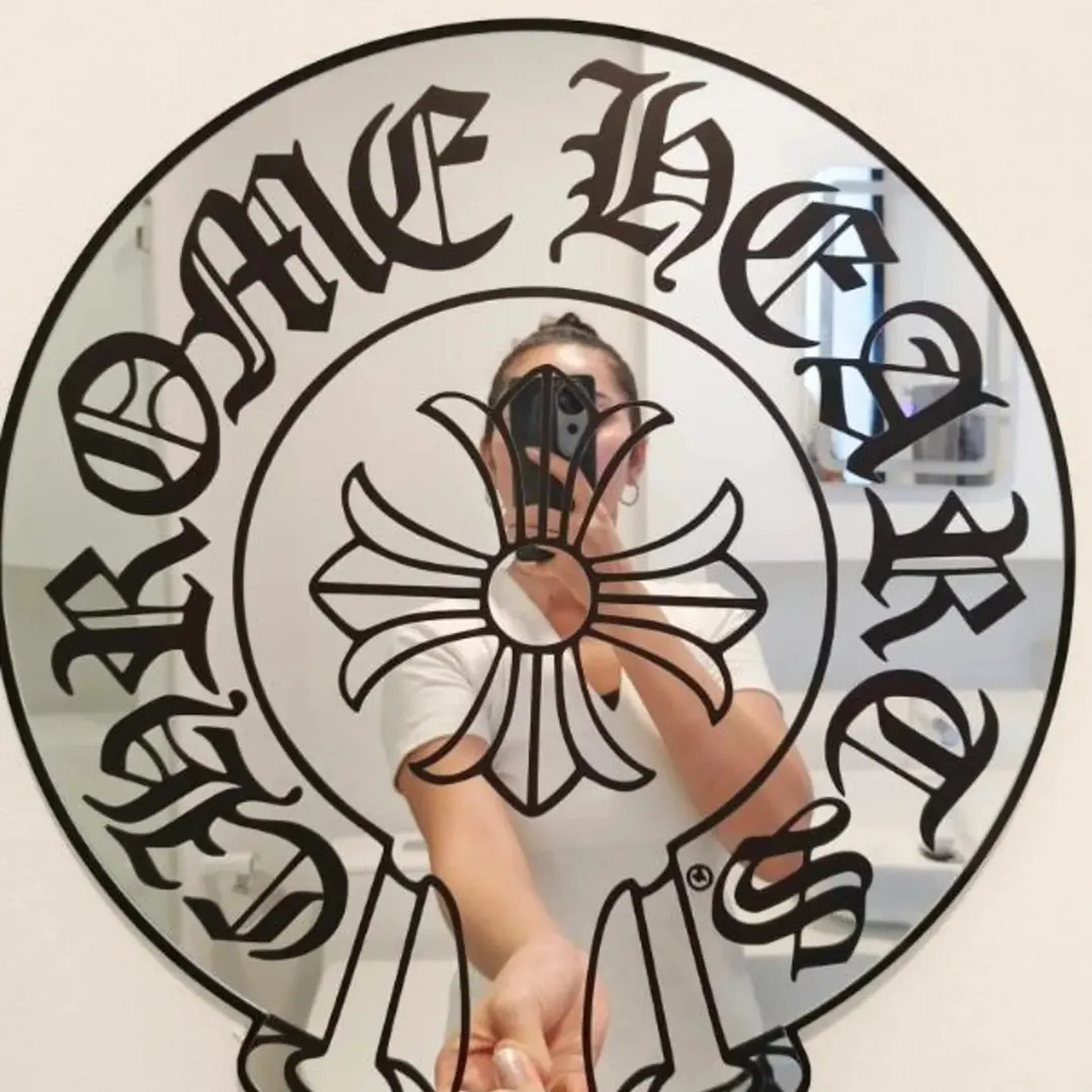 Gothic cross acrylic mirror with black old English lettering held in hand, reflective wall decor design